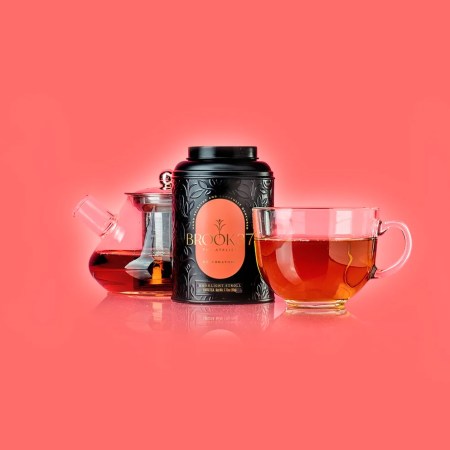 Brook37 tea, glass tea pot, and glass tea glass full of tea on a pink background